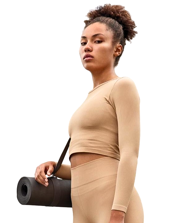 Mujer con camiseta deportiva beige de pie sujetanto un rodillo de pilates. Fondo blanco.